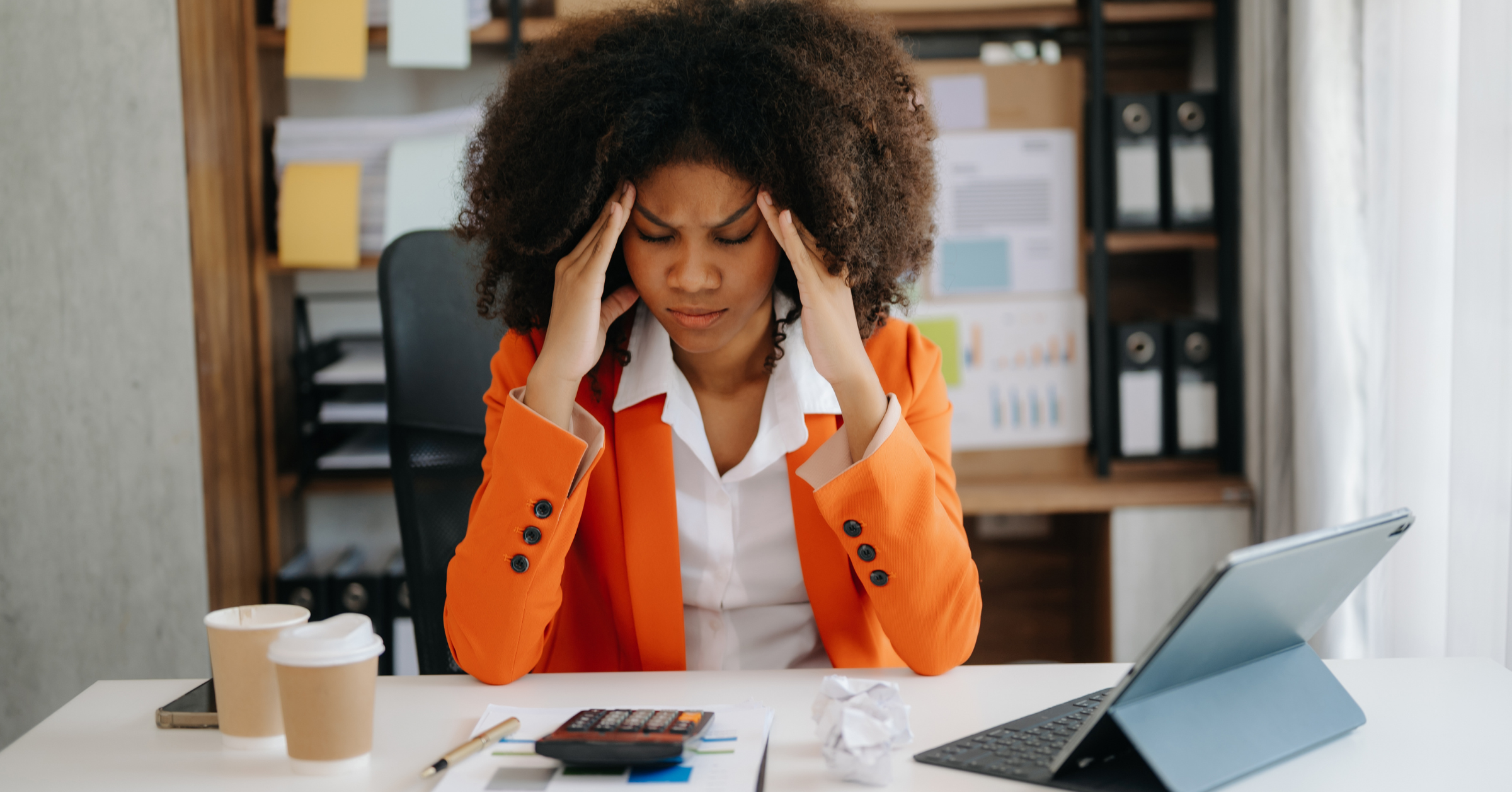 African American woman with her head in her hands appearing stressed and overwhelmed.