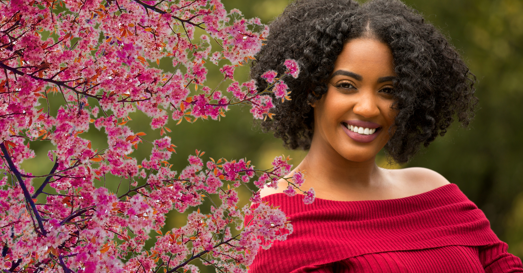 African American woman smiling under a cherry blossom tree.