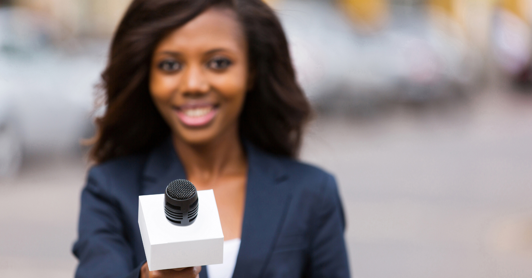 African American woman holding a microphone as she prepares to interview six influential minority women leaders.